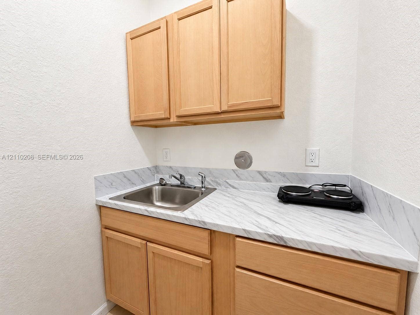657 SE 30th Terrace, #A, Homestead, Homestead, FL 33033 Light wood cabinetry featuring upper and lower storage, stone-patterned countertop, and integrated stainless steel sink with metal faucet