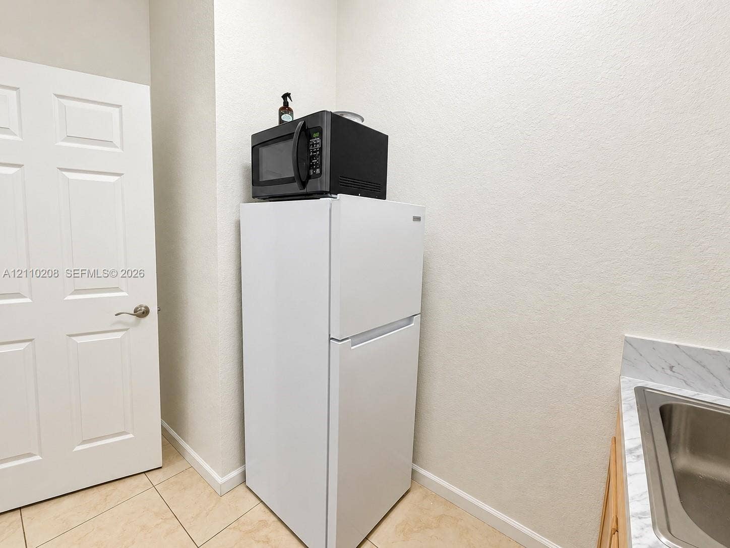 657 SE 30th Terrace, #A, Homestead, Homestead, FL 33033 Utility area featuring light-toned tile flooring, a solid-core six-panel door, and a built-in countertop with an integrated stainless steel sink basin