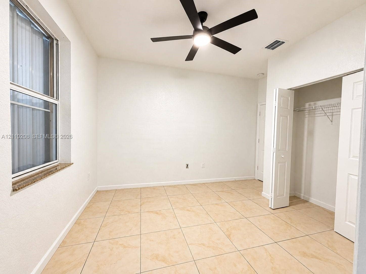 657 SE 30th Terrace, #A, Homestead, Homestead, FL 33033 Neutral-toned tile flooring, multi-pane window with stone-finish sill, integrated ceiling fan with light fixture, and closet with bifold doors