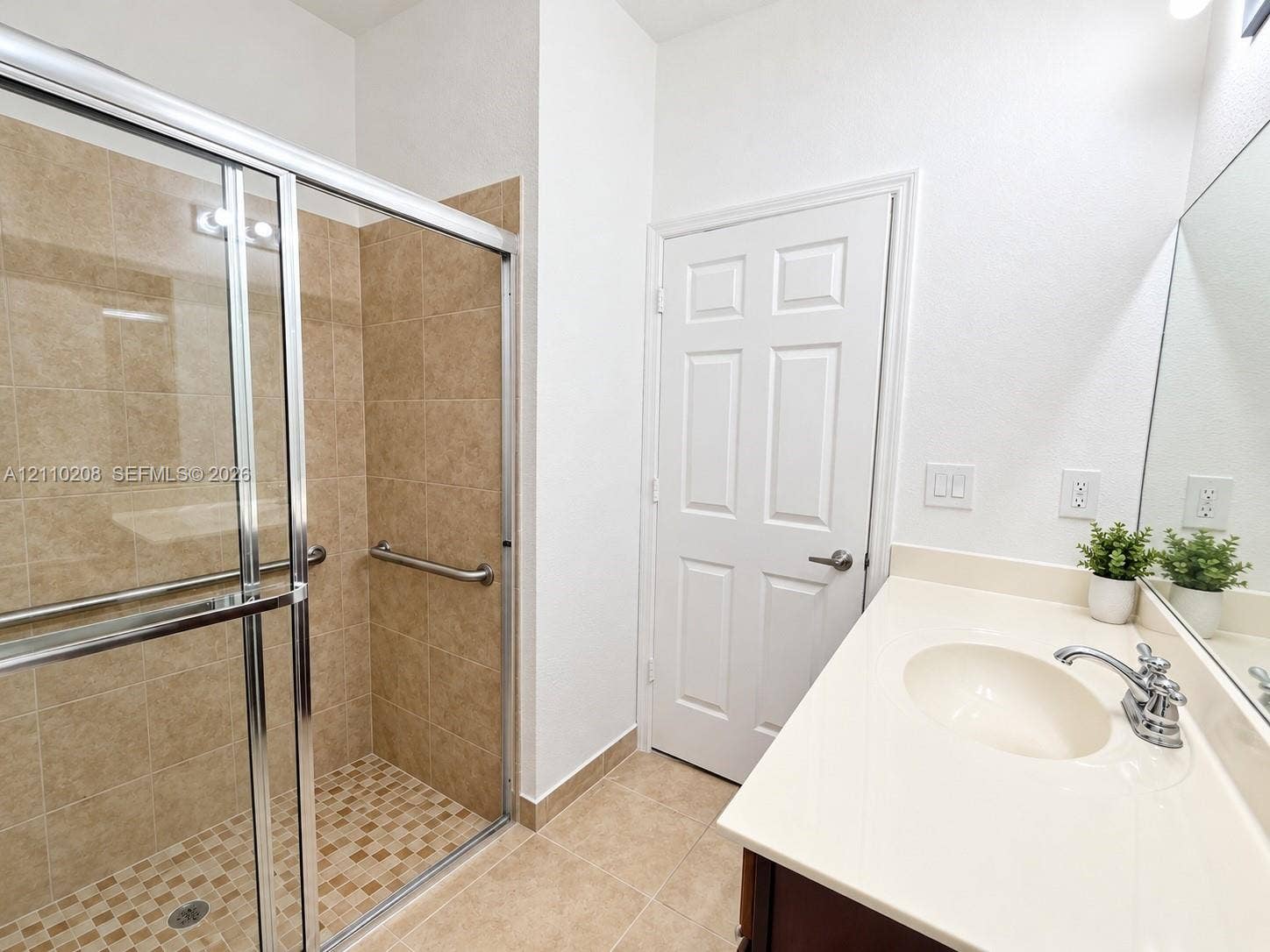 657 SE 30th Terrace, #A, Homestead, Homestead, FL 33033 Walk-in shower with tiled surround and metal grab bars, paired with a solid-surface countertop and integrated sink
