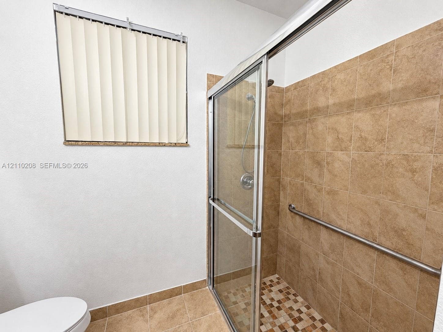 657 SE 30th Terrace, #A, Homestead, Homestead, FL 33033 Walk-in shower with sliding glass doors, neutral tile surround, integrated metal grab bar, and a mosaic tile shower floor
