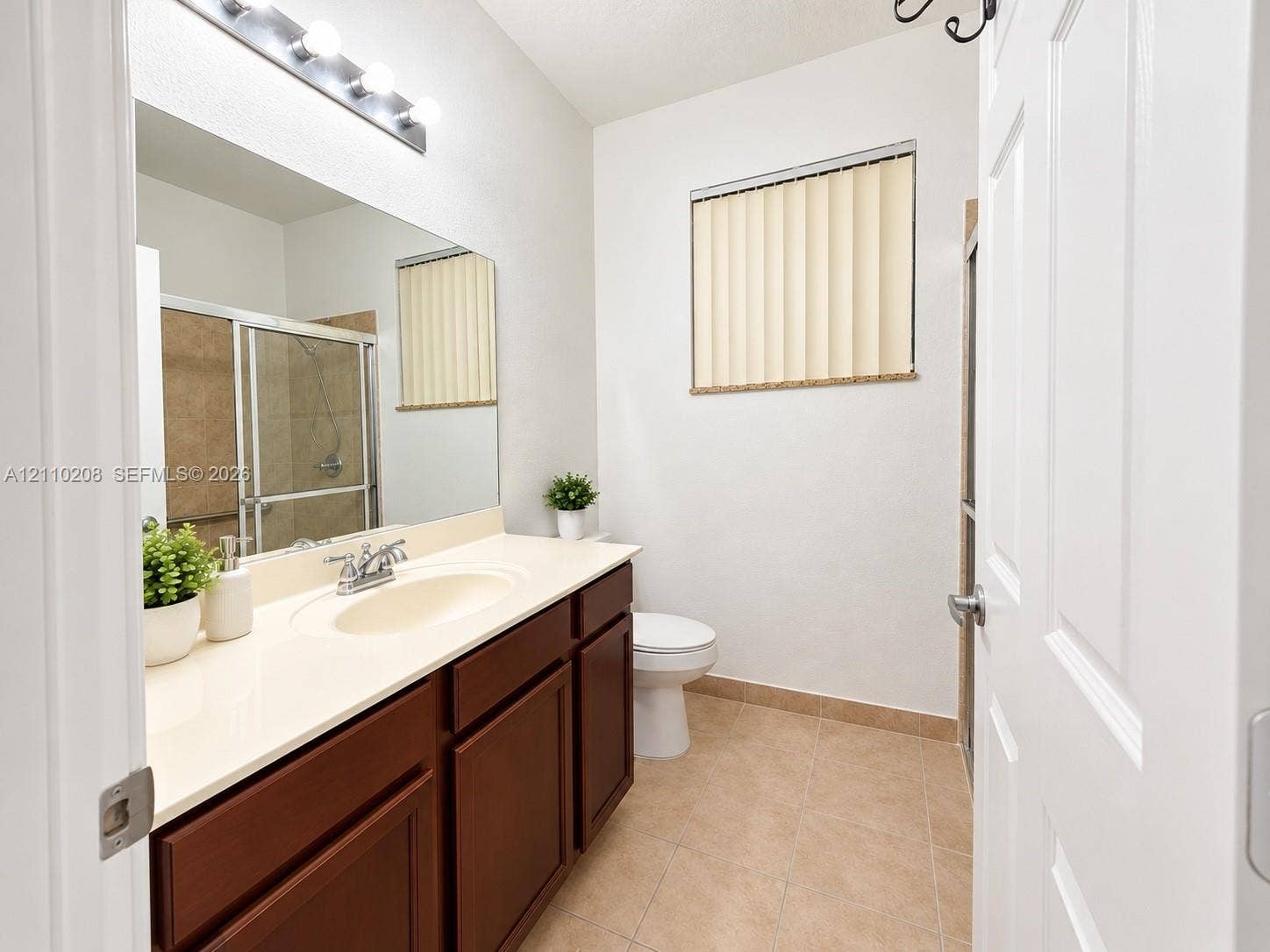 657 SE 30th Terrace, #A, Homestead, Homestead, FL 33033 Bathroom featuring a solid-surface vanity countertop, wood cabinetry, large vanity mirror, four-bulb light fixture, and tile flooring