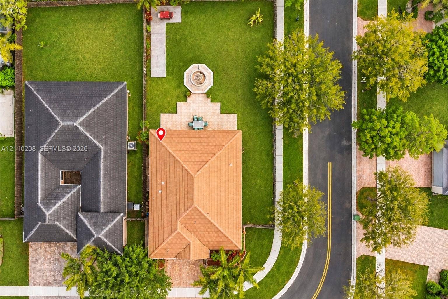 657 SE 30th Terrace, #A, Homestead, Homestead, FL 33033 Aerial perspective of a property featuring a tile roof, paved rear patio, stone-finish fountain, fenced perimeter, and manicured lawn