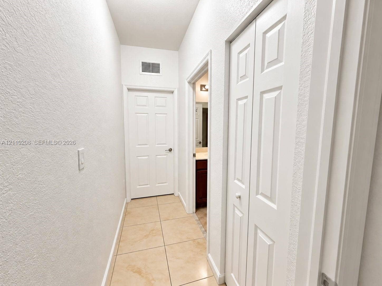 657 SE 30th Terrace, #A, Homestead, Homestead, FL 33033 Neutral-toned floor tiling, textured walls, white six-panel interior door, and white bi-fold closet doors