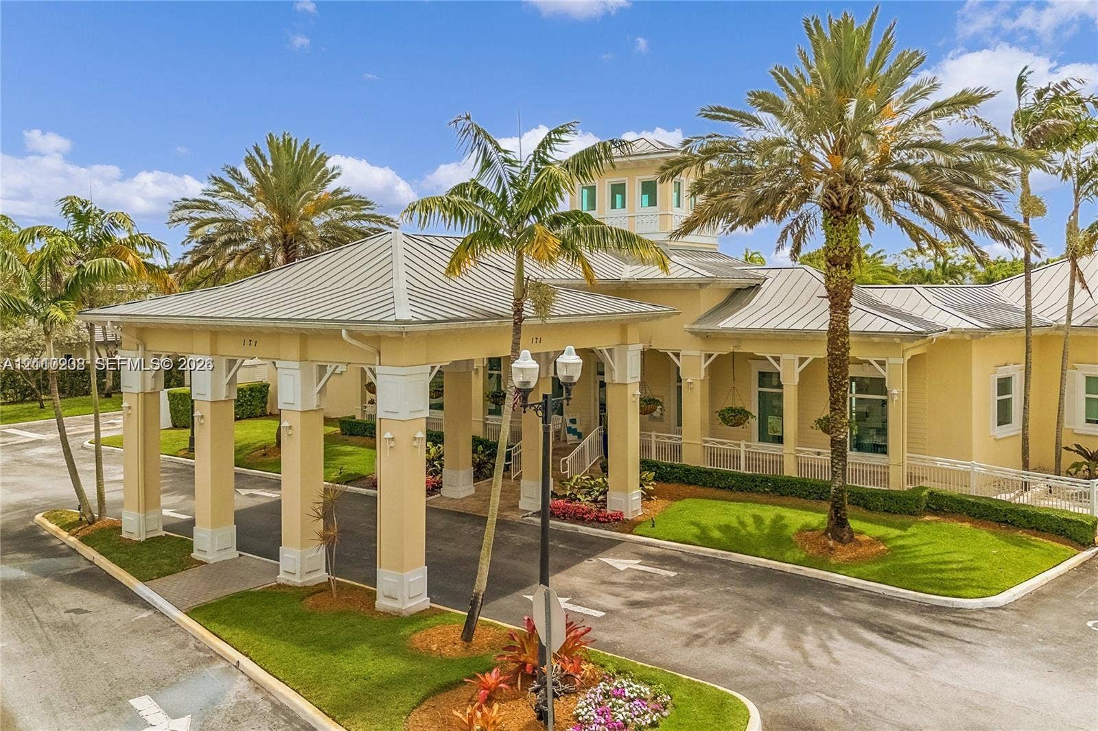 657 SE 30th Terrace, #A, Homestead, Homestead, FL 33033 Covered porte-cochre with architectural columns, metal roof, cupola, and landscaped grounds featuring mature palm trees