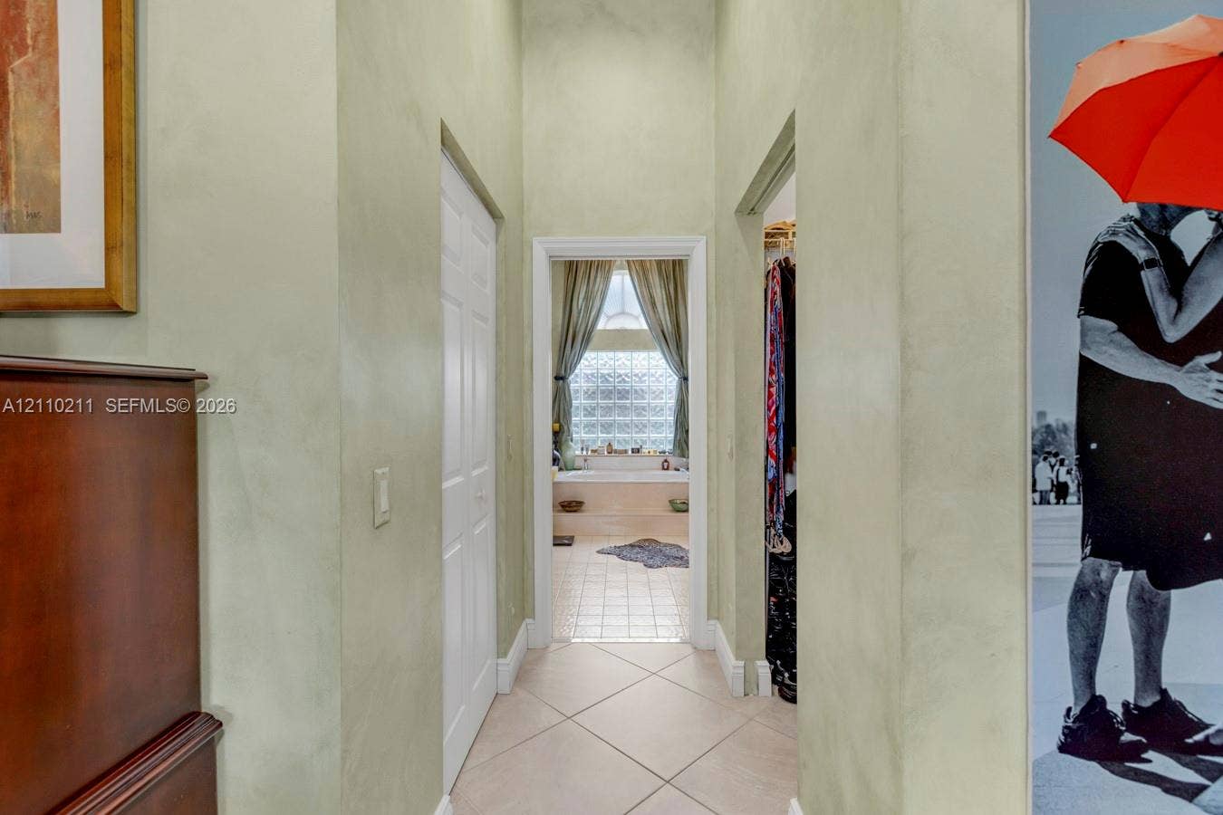 Bathroom featuring a recessed soaking tub with a tiled surround, glass block window, separate shower stall with a glass enclosure, and dual cabinetry with dark stone countertops