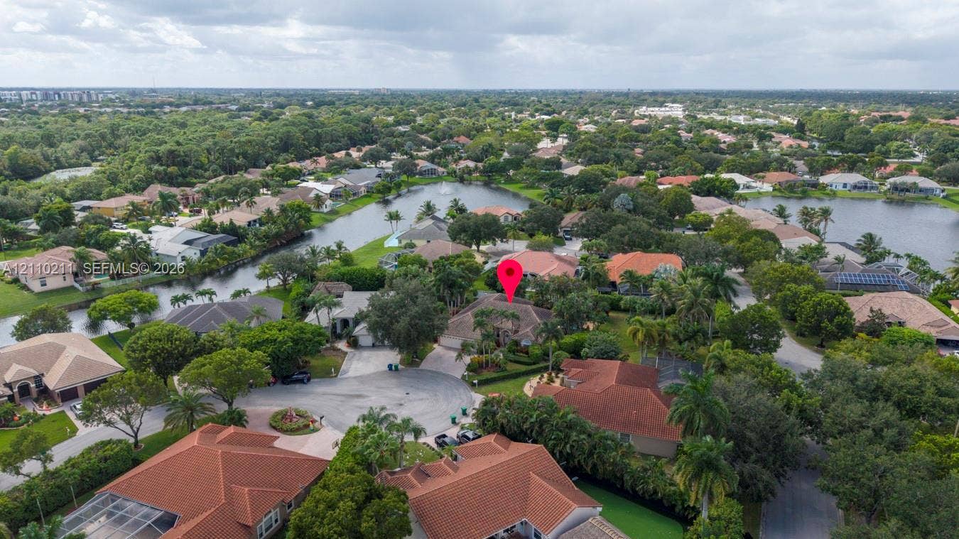 Aerial perspective of a property featuring a cul-de-sac location, tile roofing, and mature perimeter landscaping