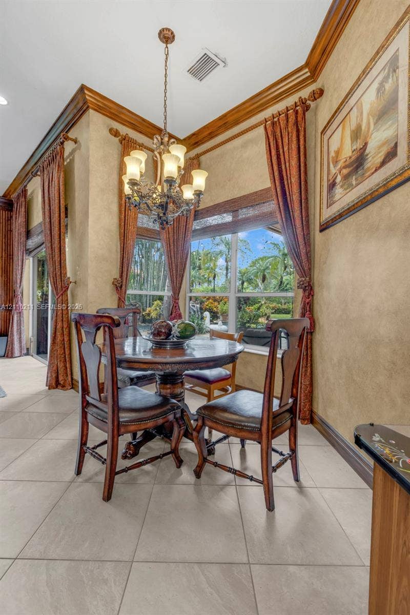 Large-format tile flooring, multi-pane windows, ornate metal chandelier, and detailed crown molding