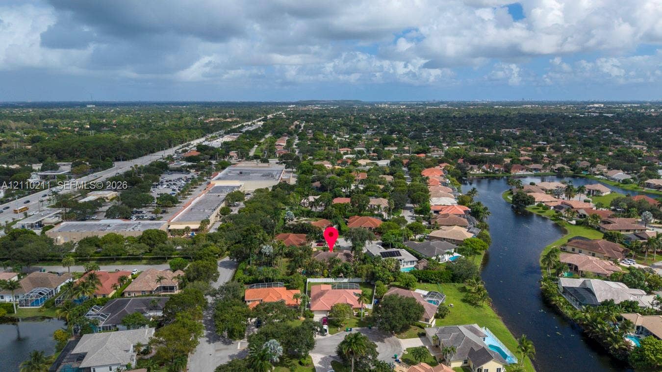 Aerial perspective of a residential community featuring extensive mature canopy trees, winding neighborhood roads, and proximity to a waterway