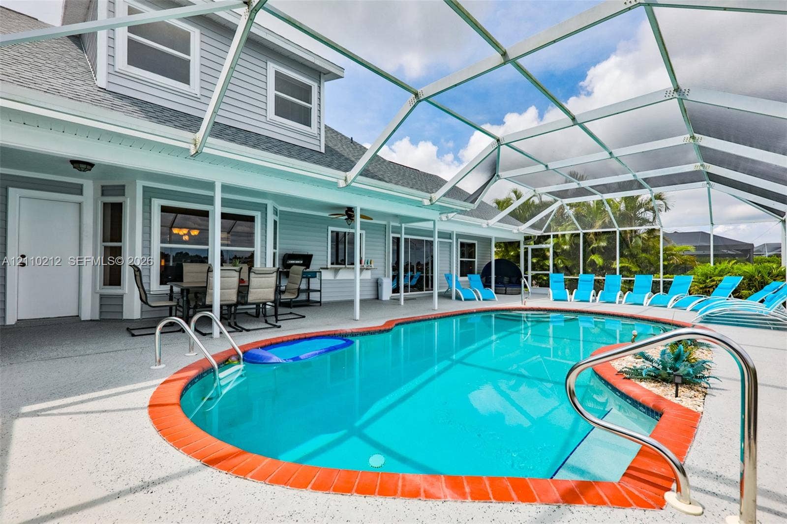 407 SW 37, Cape Coral, FL 33914 Screen-enclosed patio with a concrete deck, kidney-shaped swimming pool with terracotta-style brick coping, built-in pass-through window, and lap siding exterior