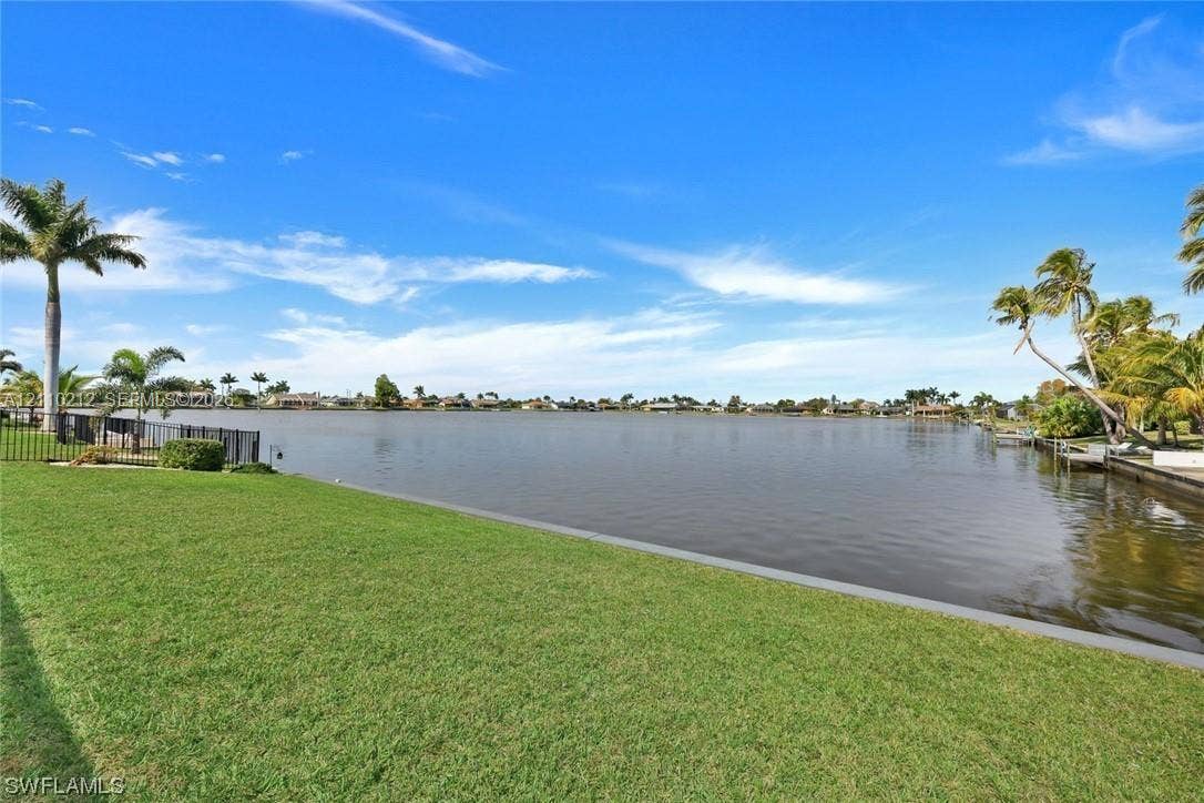 407 SW 37, Cape Coral, FL 33914 Waterfront lot featuring a manicured lawn, concrete seawall, and mature palm trees