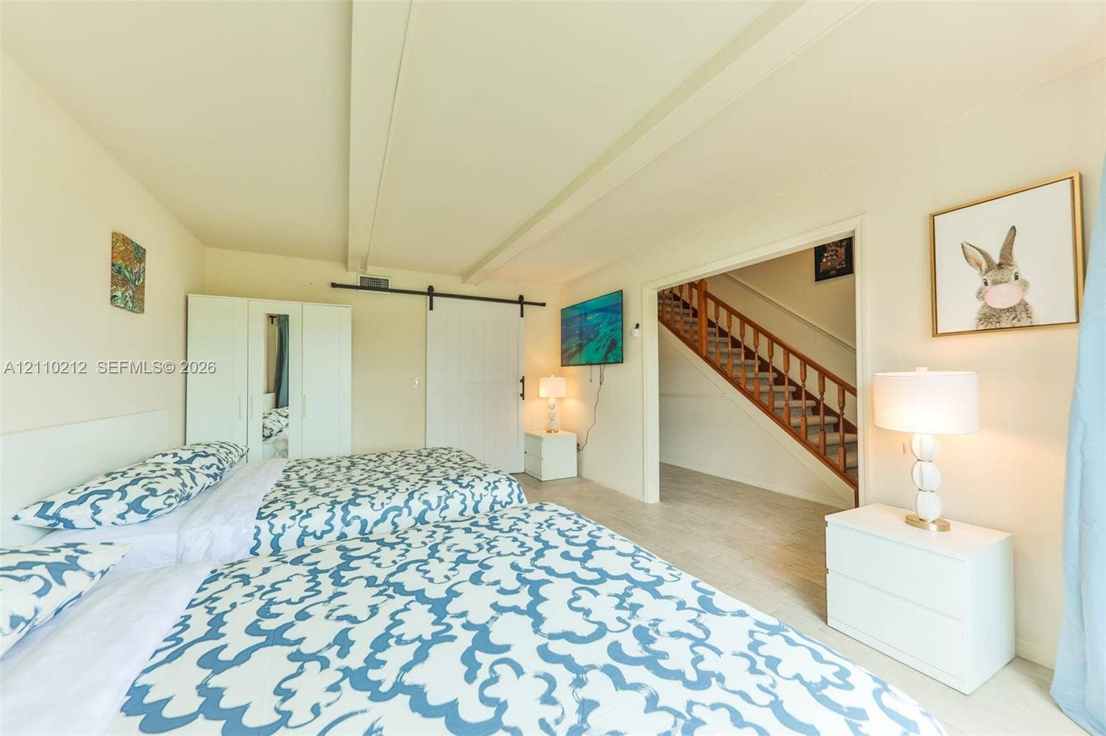 407 SW 37, Cape Coral, FL 33914 Room featuring neutral wall tones, exposed structural ceiling beams, a sliding barn-style door, and light-toned flooring