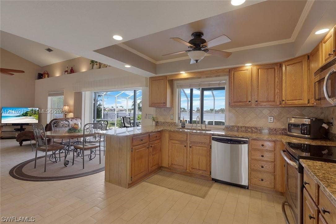407 SW 37, Cape Coral, FL 33914 Kitchen featuring wood cabinetry, stone-finish countertops, stainless steel dishwasher, tile flooring, and a tray ceiling