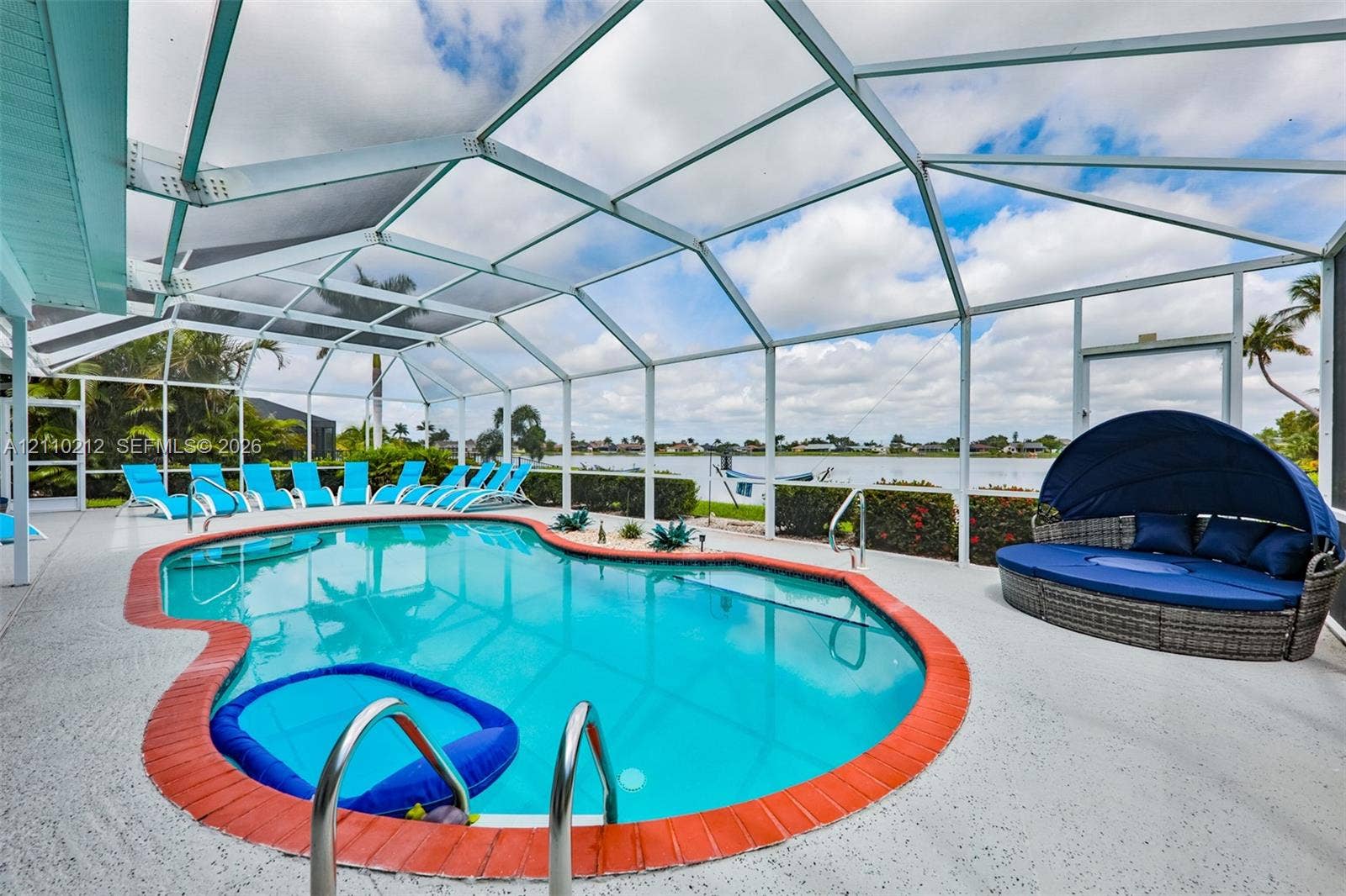 407 SW 37, Cape Coral, FL 33914 Screen-enclosed swimming pool featuring a brick-paver border, concrete decking, metal pool ladder, and waterfront positioning