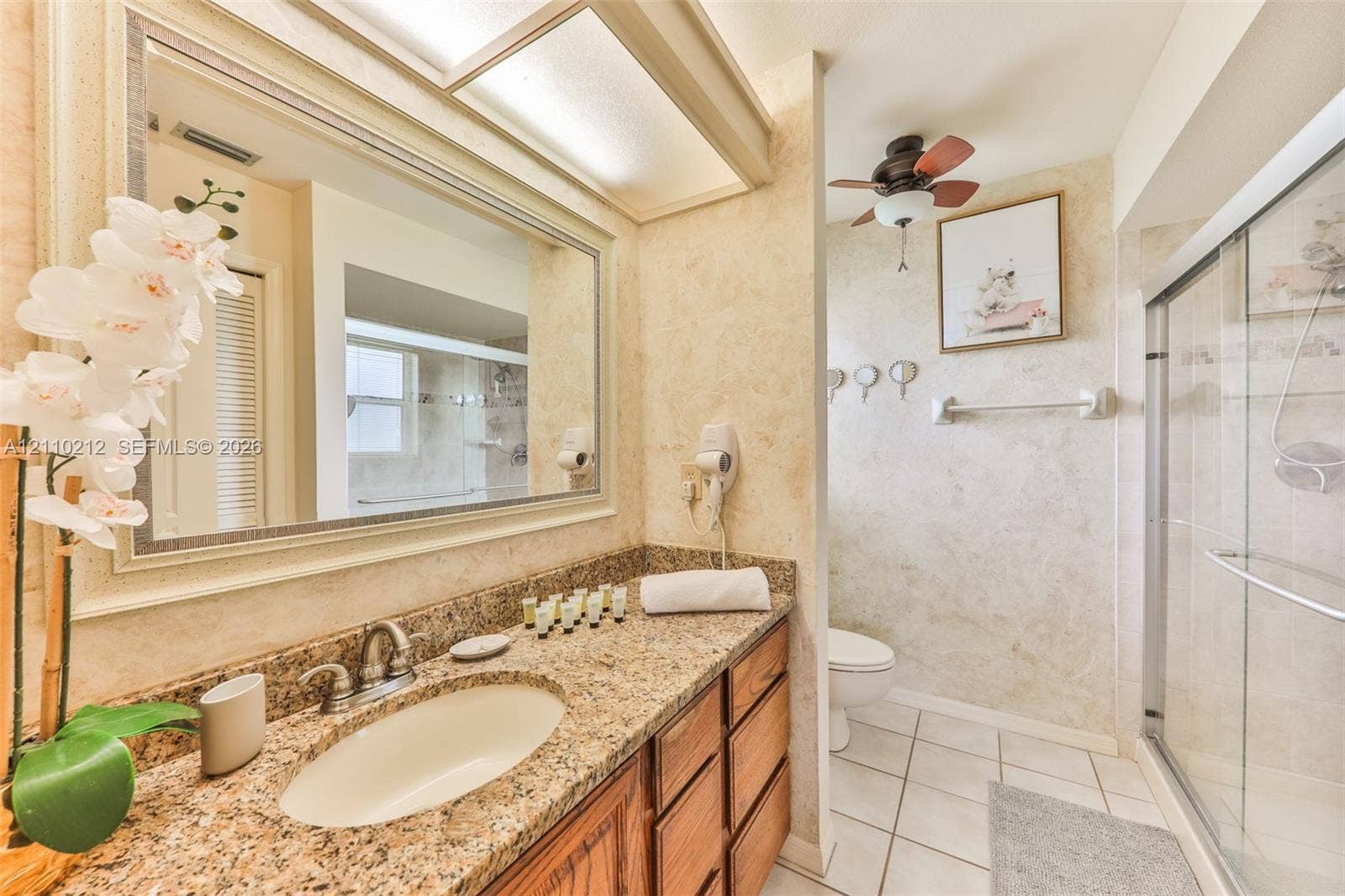 407 SW 37, Cape Coral, FL 33914 Stone countertop with integrated oval sink, wood-finish cabinetry, framed vanity mirror, overhead lighting fixture, and a glass-enclosed shower