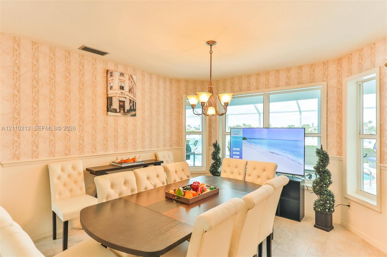 407 SW 37, Cape Coral, FL 33914 Dining area featuring expansive bay windows, crown-style metal chandelier, and chair rail molding