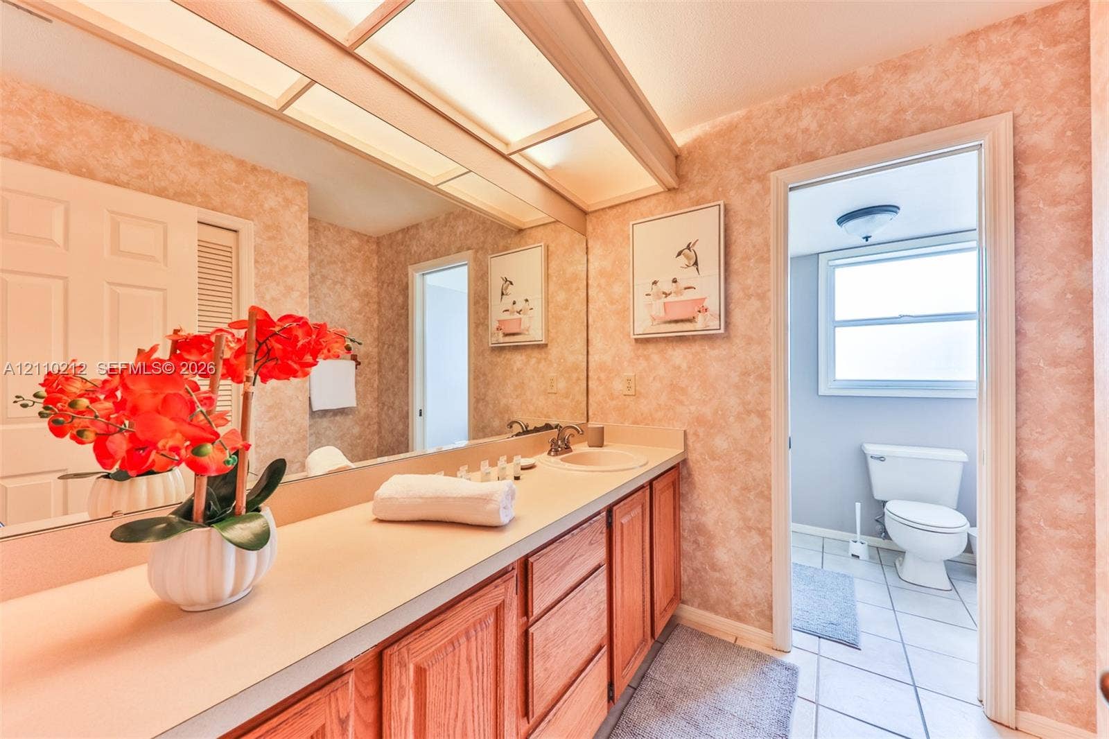 407 SW 37, Cape Coral, FL 33914 Bathroom featuring wood cabinetry, solid-surface countertop with an integrated sink, full-width wall mirror, and overhead soffit lighting