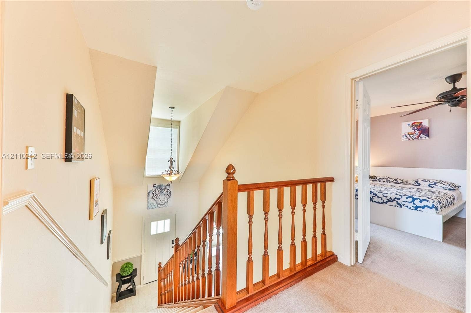 407 SW 37, Cape Coral, FL 33914 Staircase featuring wood railings and balusters, tiered landing, suspended pendant light fixture, and neutral wall color