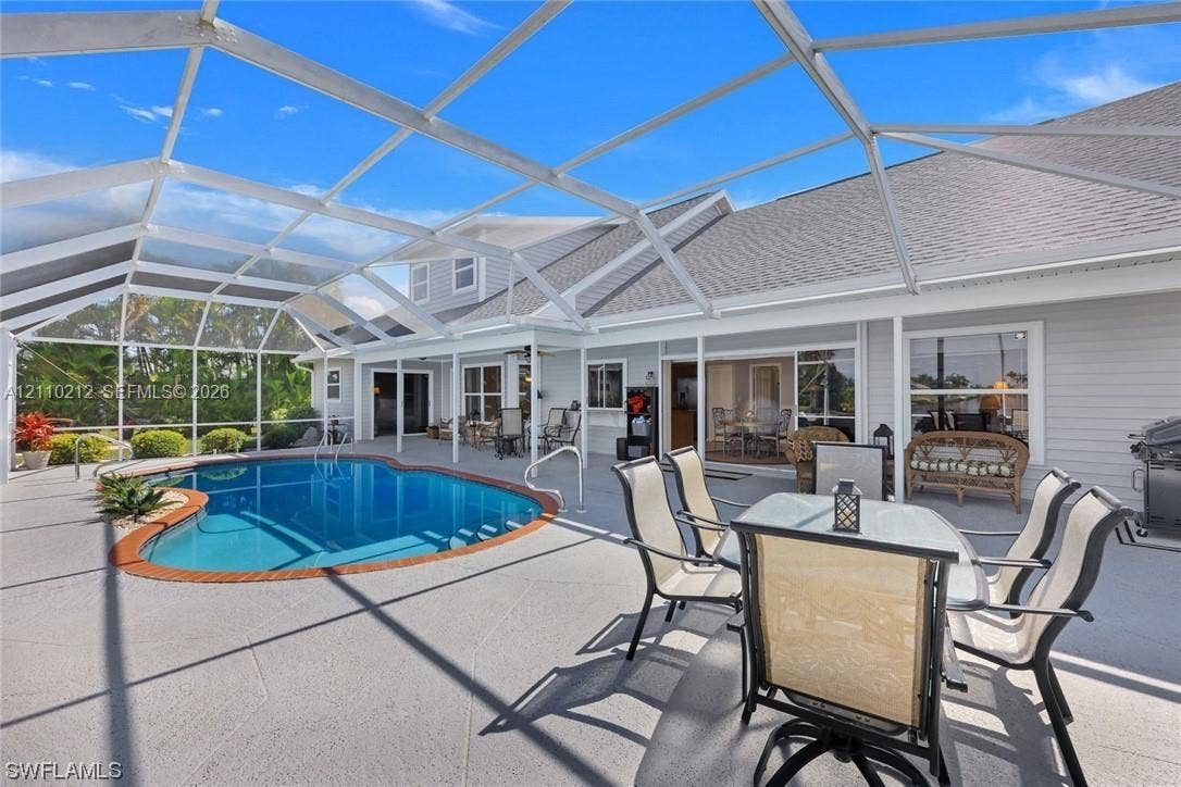 407 SW 37, Cape Coral, FL 33914 Screened-in patio featuring a concrete deck and a kidney-shaped pool with a decorative brick border