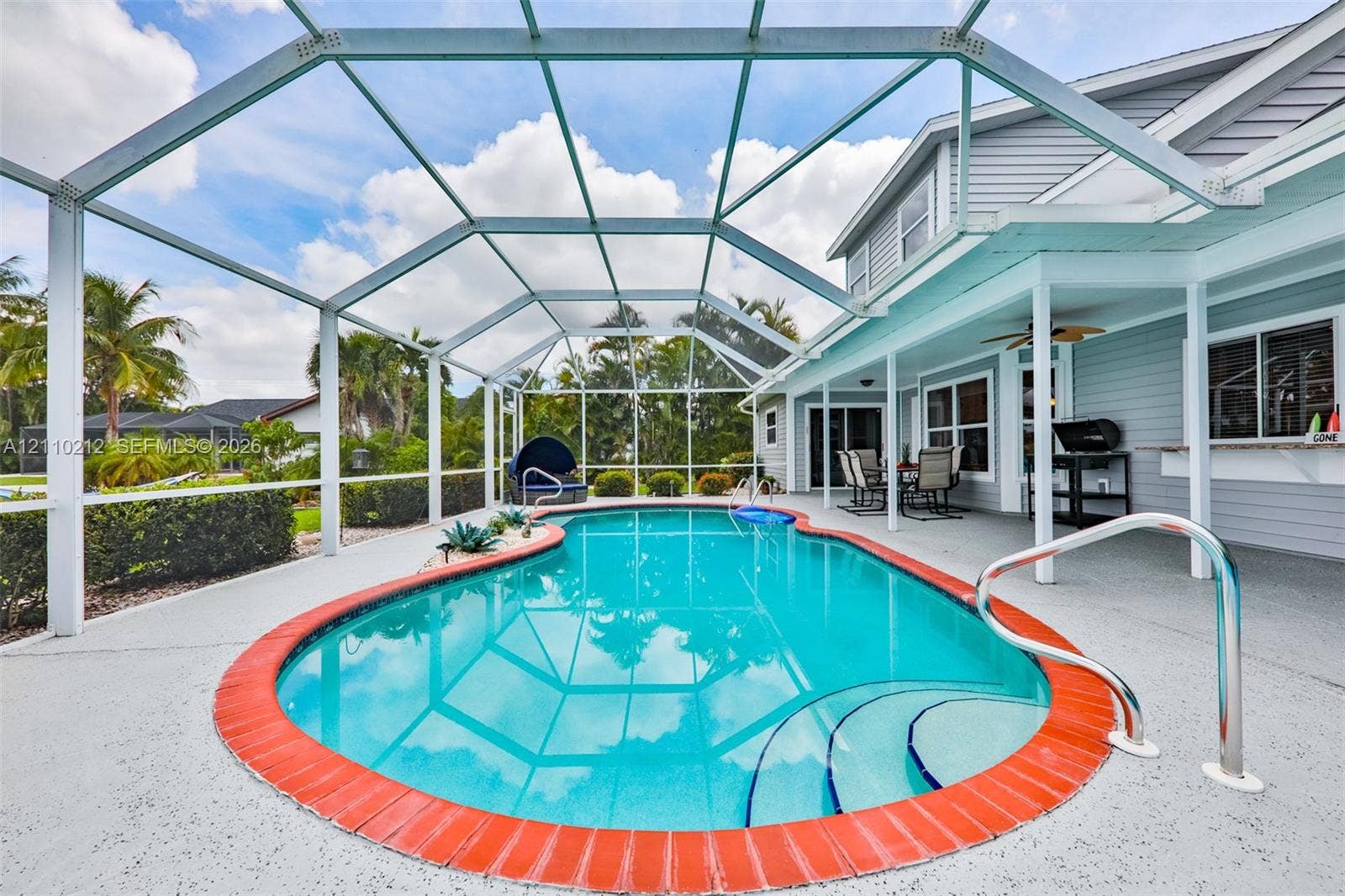 407 SW 37, Cape Coral, FL 33914 Screen-enclosed swimming pool featuring a brick-accented border, concrete deck, integrated steps, and covered patio area