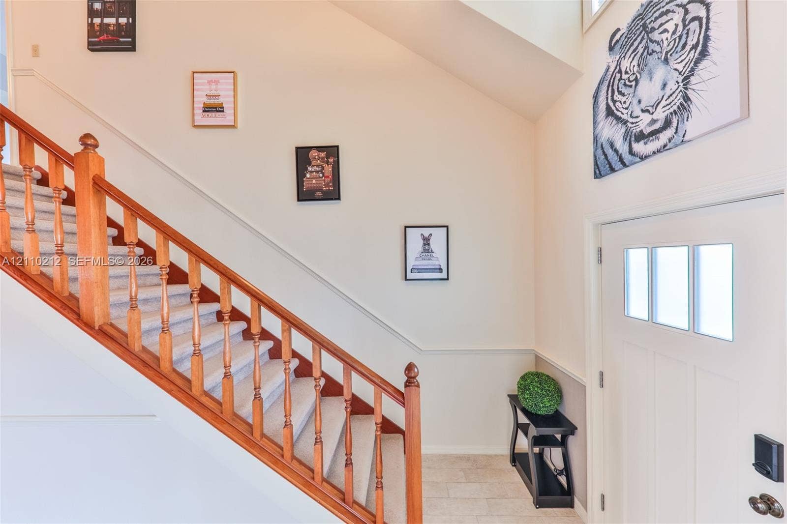 407 SW 37, Cape Coral, FL 33914 Entryway featuring a staircase with wood railings and balusters, carpeted treads, high ceilings, stone-finish flooring, and a white entry door with a three-pane window