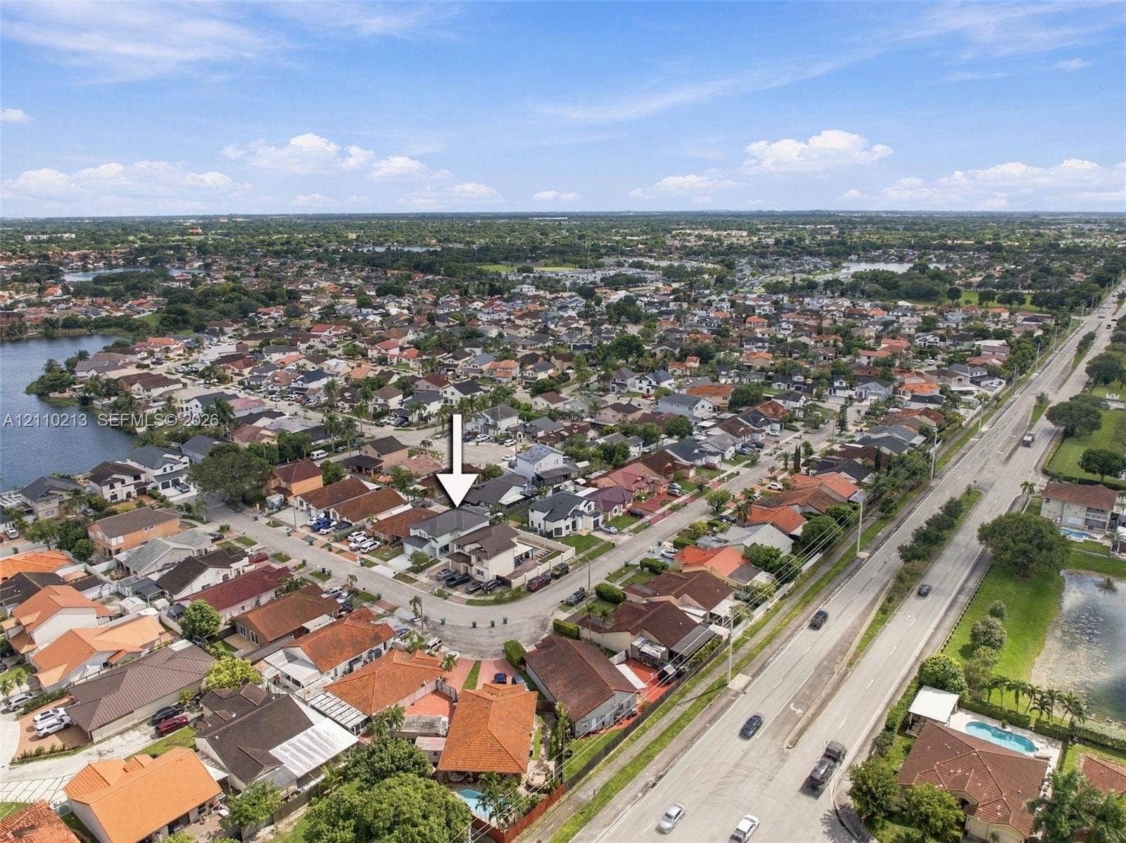 Aerial perspective of a single-family residence situated on a corner lot within a residential community, featuring a multi-pitched roofline and a concrete driveway