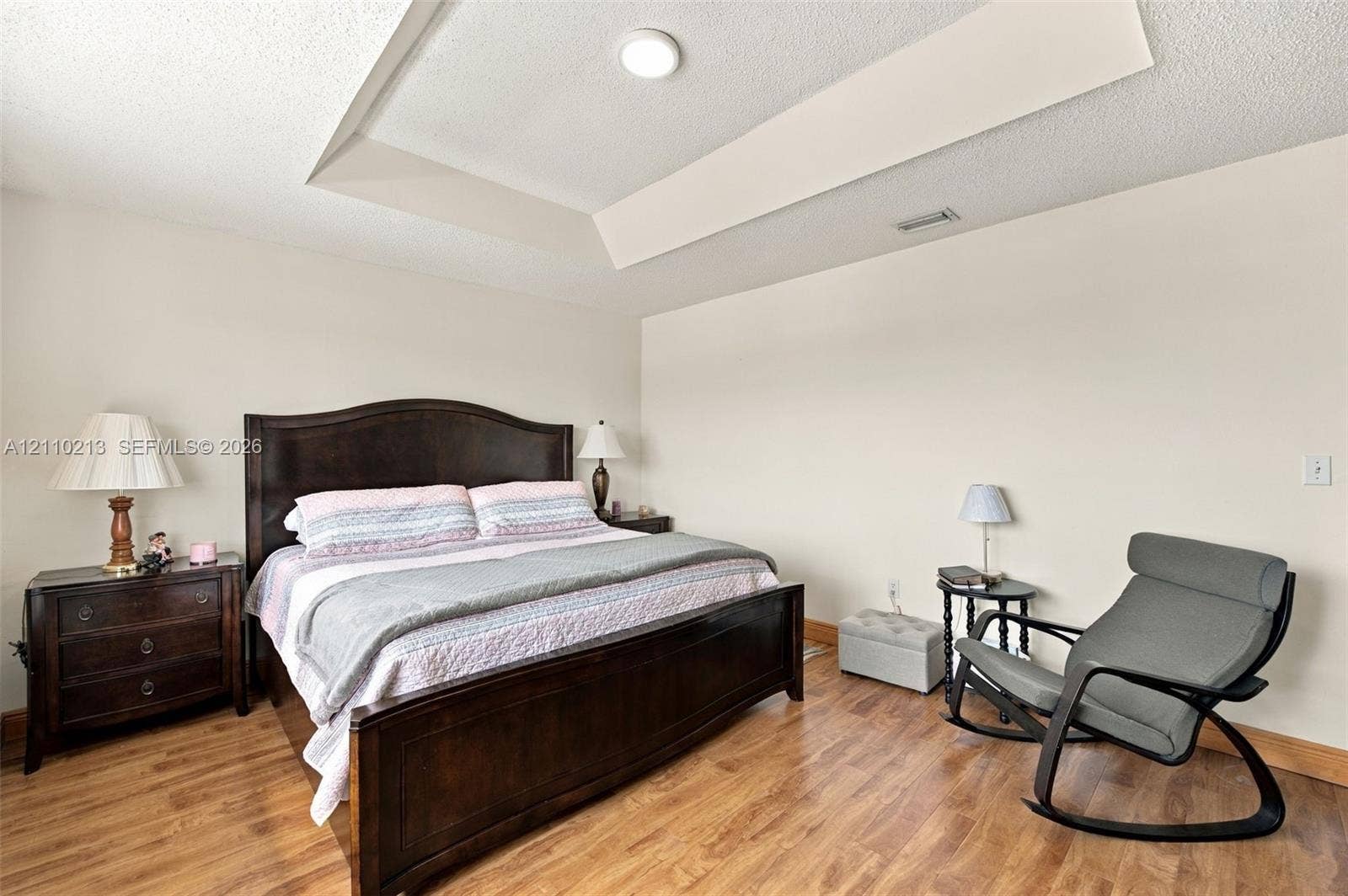 Room featuring a tray ceiling and wood-finish flooring