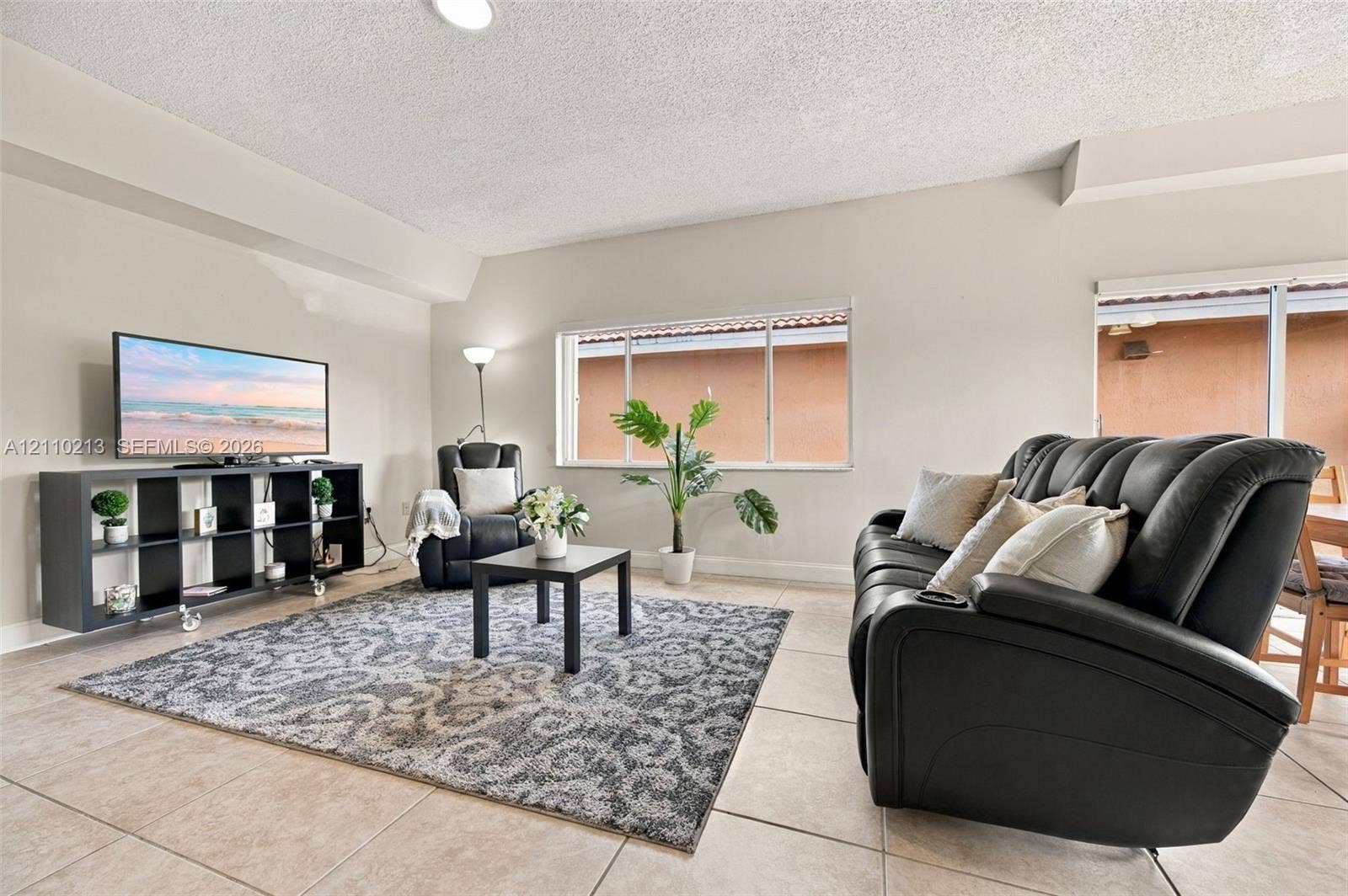 Neutral-toned interior space featuring light-colored ceramic tile flooring, horizontal sliding windows, and a sliding glass door providing access to the exterior