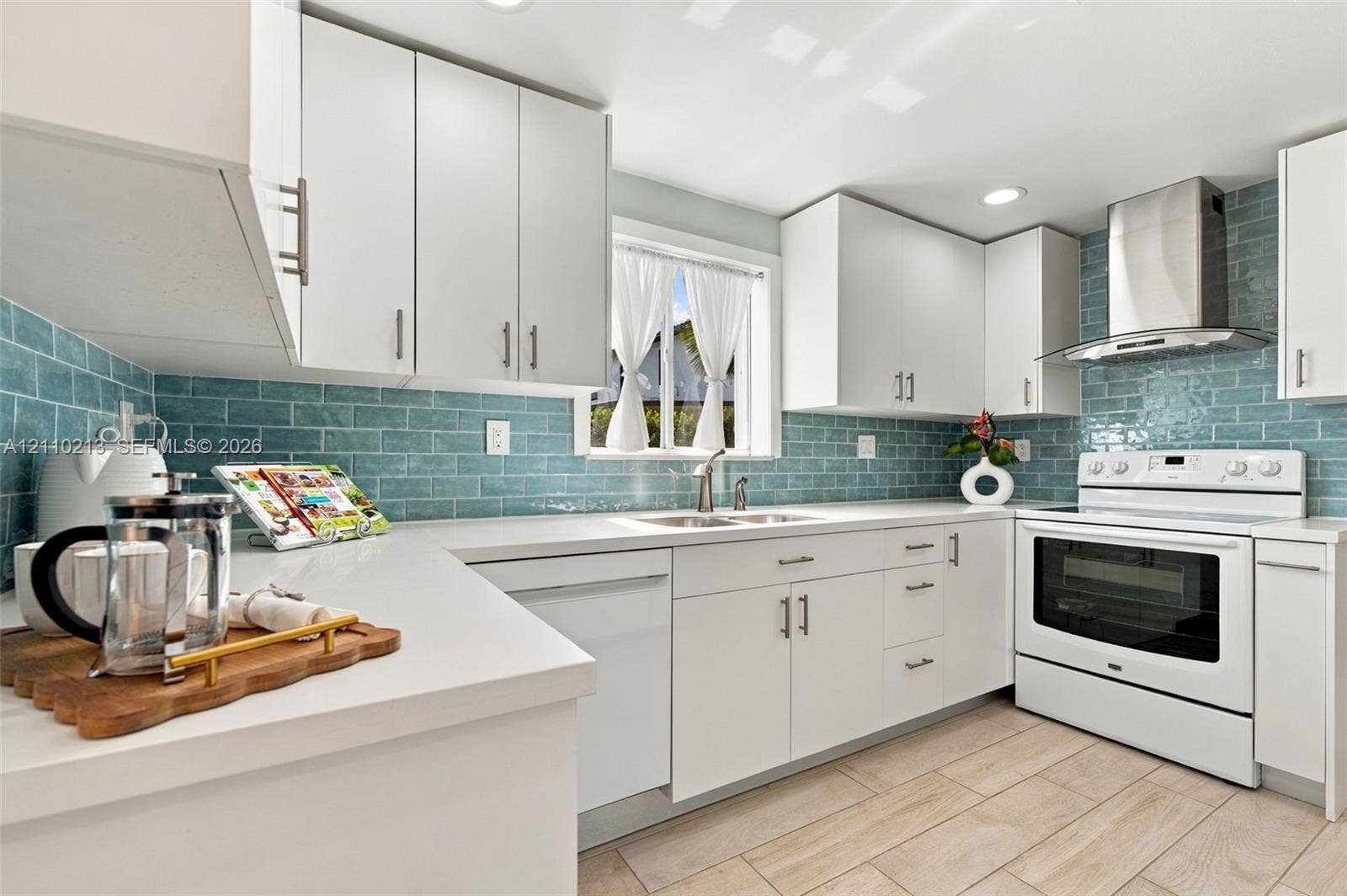 Kitchen featuring white cabinetry, solid-surface countertops, blue subway tile backsplash, stainless steel range hood, and wood-finish flooring
