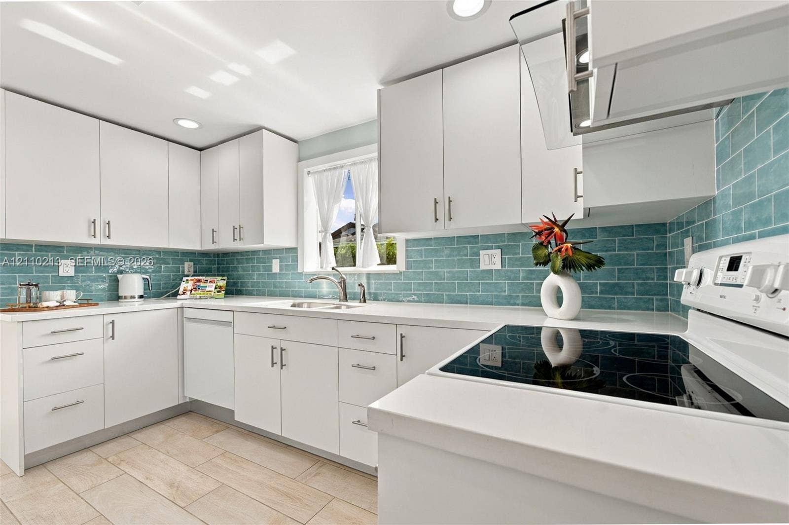 Kitchen featuring white shaker-style cabinetry, solid-surface countertops, blue subway tile backsplash, built-in electric range, and wood-finish flooring