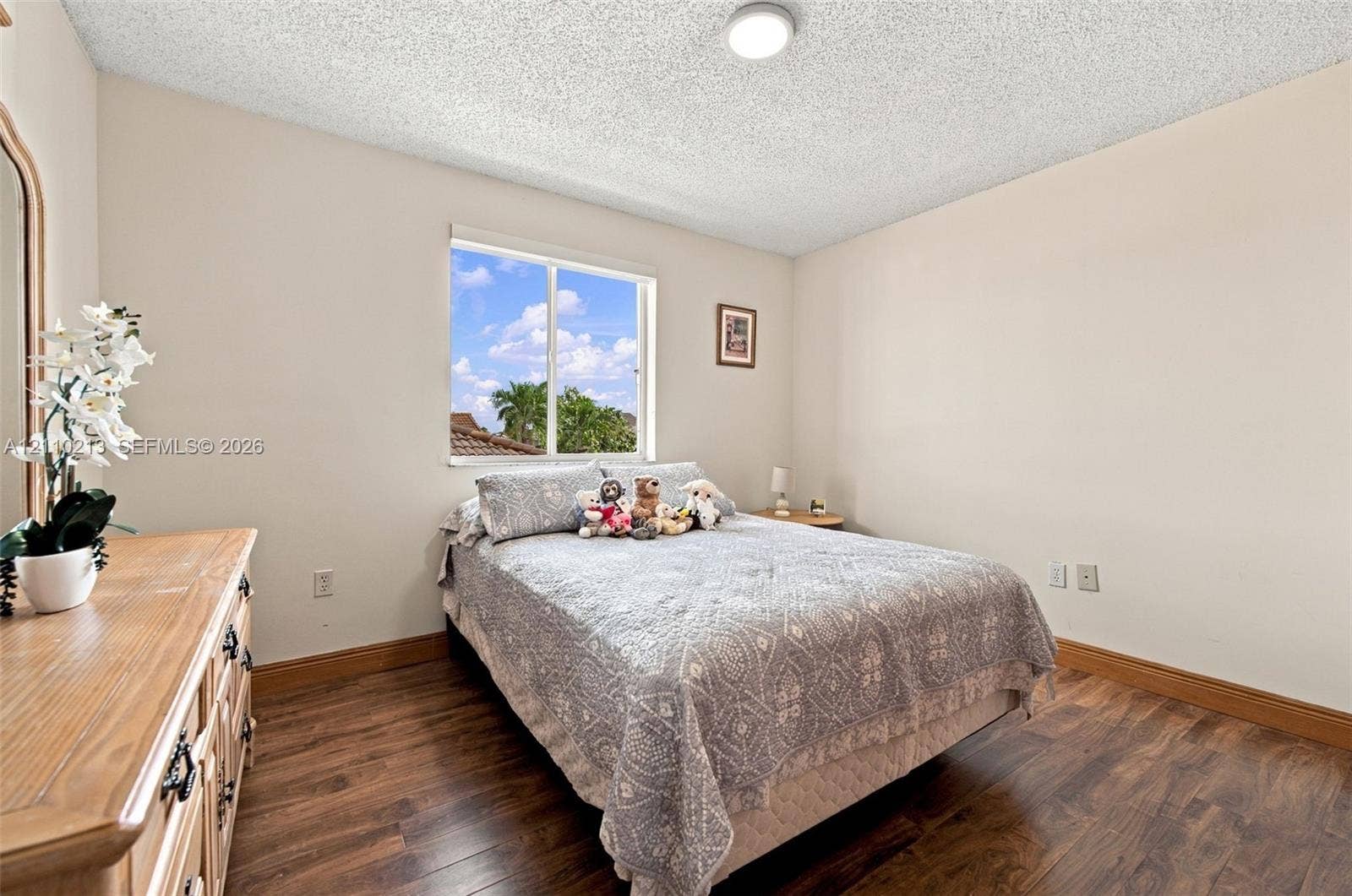 Neutral-toned interior room featuring wood-finish flooring, a ceiling-mounted light fixture, and a single-pane sliding window