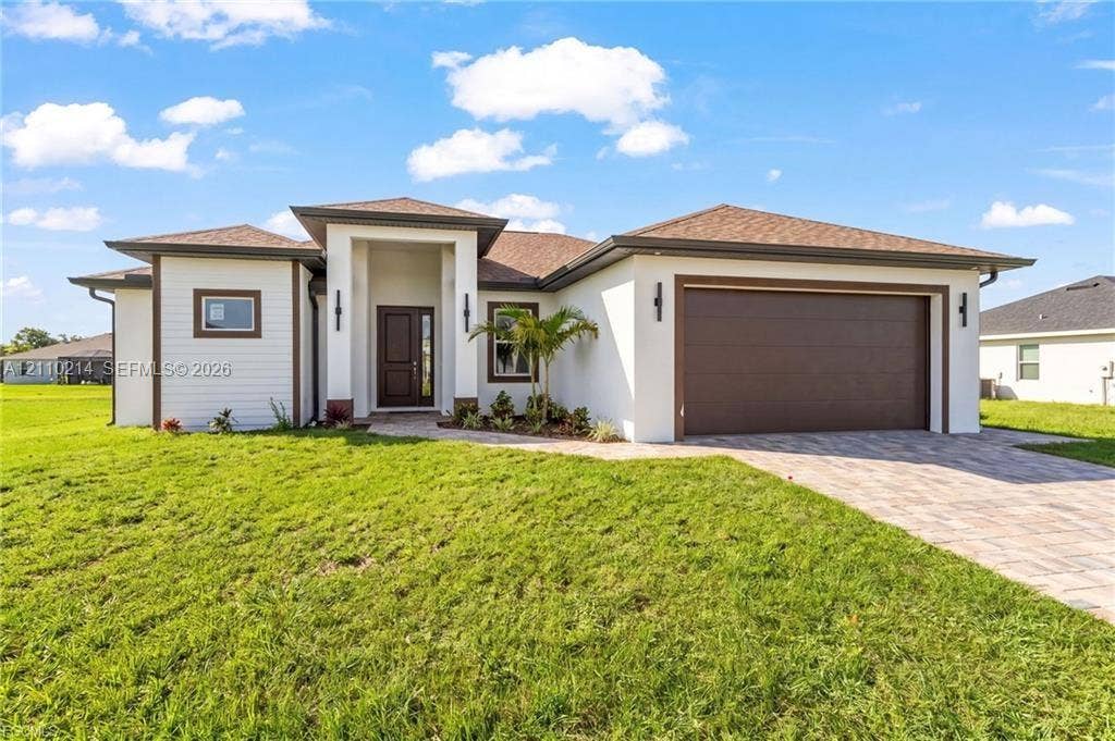 7 SW 19th Place, Cape Coral, FL 33991 Contemporary stucco exterior featuring a covered entryway, multi-tone shingle roof, two-car garage, and paver driveway