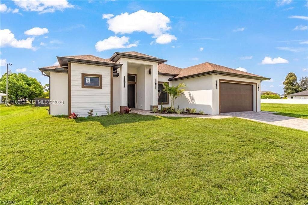 7 SW 19th Place, Cape Coral, FL 33991 Stucco and horizontal siding exterior featuring a hip roof, covered entryway, and an attached two-car garage