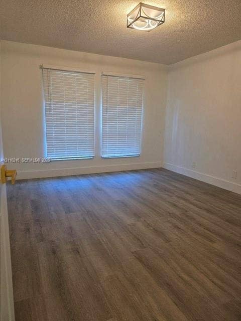 Room featuring wood-finish flooring, dual windows with horizontal blinds, and a geometric flush-mount ceiling light fixture