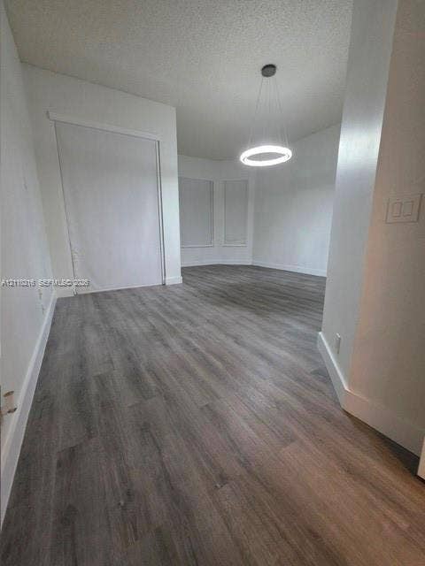 Neutral interior space featuring wood-finish flooring, a contemporary circular pendant light fixture, and a built-in closet with sliding doors
