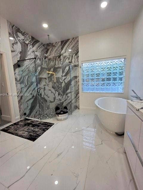 Walk-in shower with floor-to-ceiling patterned stone tile, glass enclosure, and rainfall showerhead, complemented by a freestanding soaking tub, glass block window, and large-format porcelain tile flooring