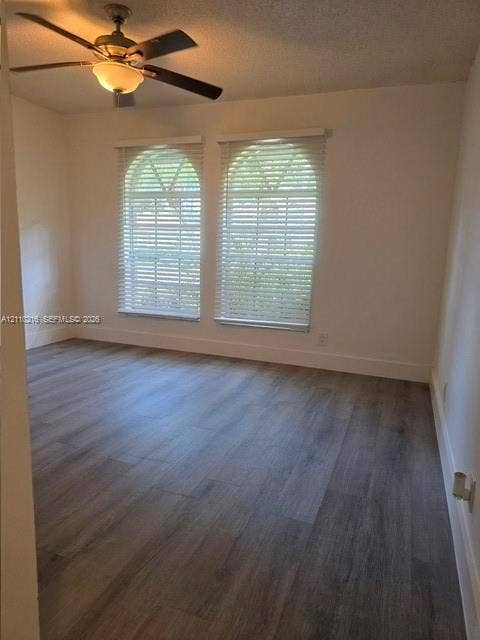 Bright corner room featuring dual French doors with plantation shutters, wood-finish flooring, and ceiling fan with integrated lighting fixture