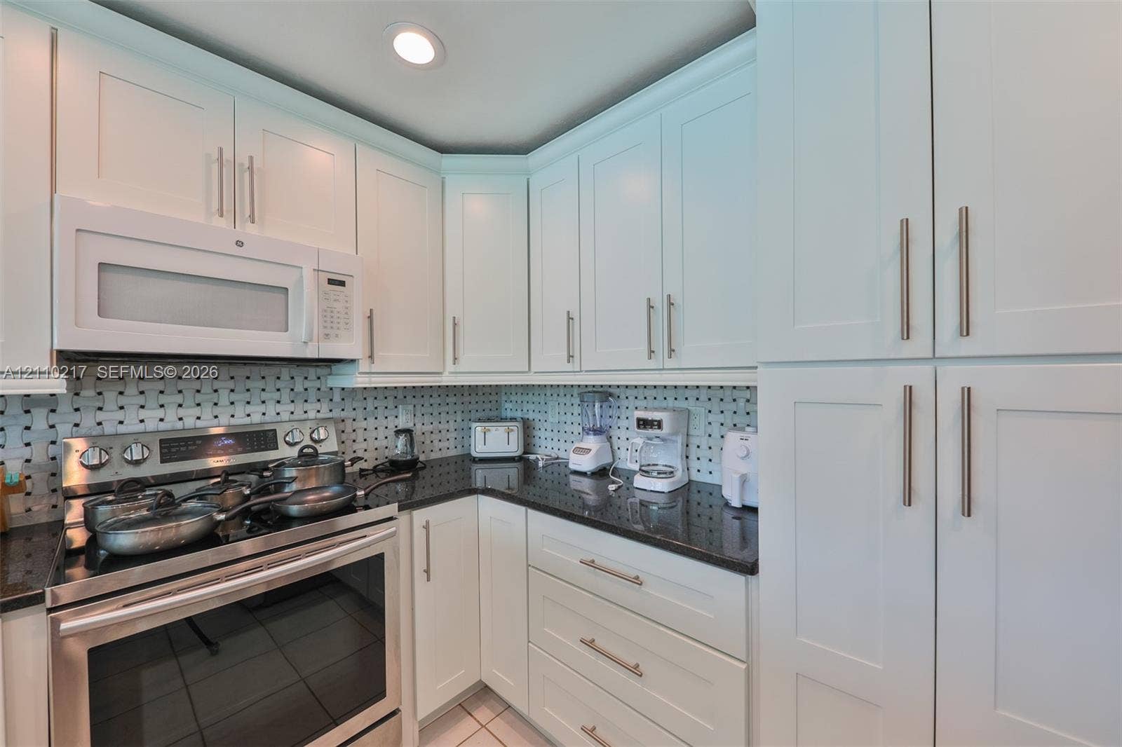 503 SW 17 Street, Cape Coral, FL 33990 Kitchen featuring white shaker-style cabinetry, dark stone countertops, stainless steel appliances, and a geometric tile backsplash