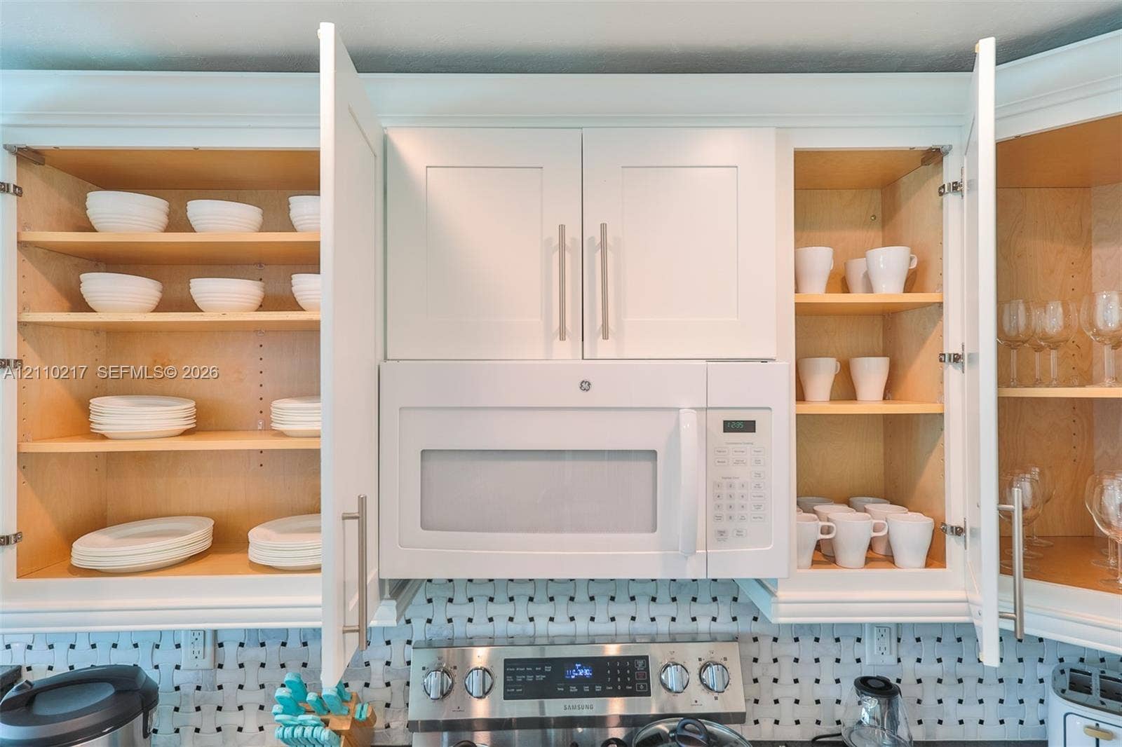 503 SW 17 Street, Cape Coral, FL 33990 Shaker-style white cabinetry with adjustable shelving and brushed nickel hardware, featuring a built-in over-the-range microwave and a patterned geometric backsplash