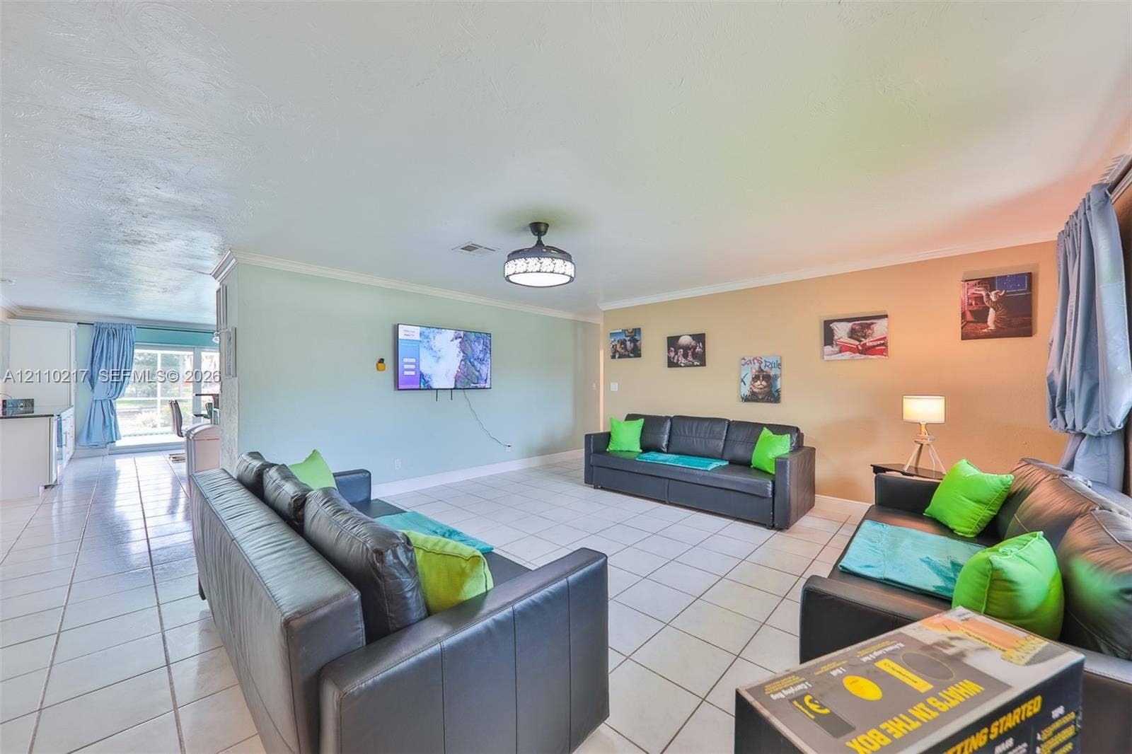 503 SW 17 Street, Cape Coral, FL 33990 Open-concept interior featuring light-colored tile flooring, a central ceiling fan with integrated lighting, and crown molding