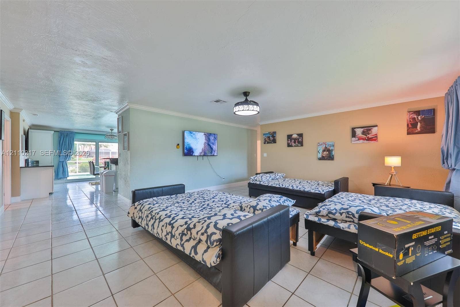 503 SW 17 Street, Cape Coral, FL 33990 Open-concept living space featuring large-format tile flooring, a mounted ceiling fan with integrated lighting, and sliding glass doors