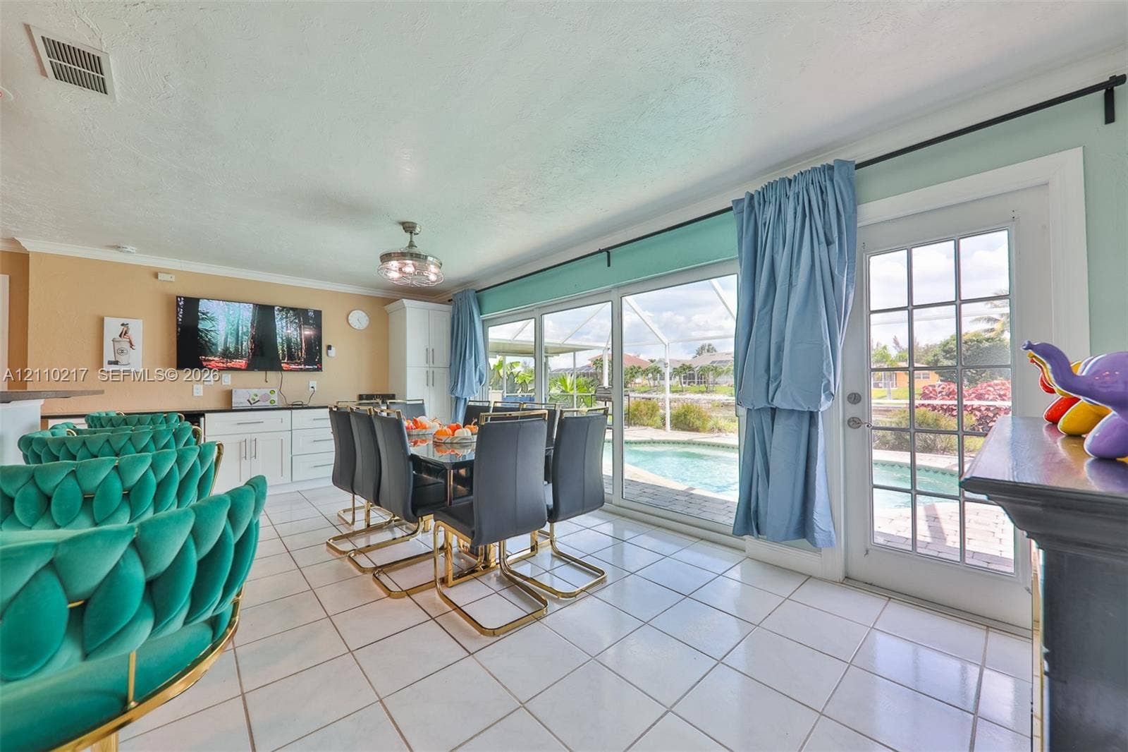 503 SW 17 Street, Cape Coral, FL 33990 Ceramic tile flooring, built-in cabinetry with dark countertops, three-panel sliding glass doors, and a full-light glass entry door opening to an enclosed pool area