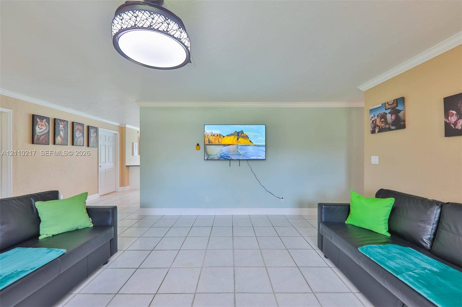 503 SW 17 Street, Cape Coral, FL 33990 Neutral-toned room featuring large-format square tile flooring, crown molding, and a decorative semi-flush mount ceiling fixture with a patterned shade
