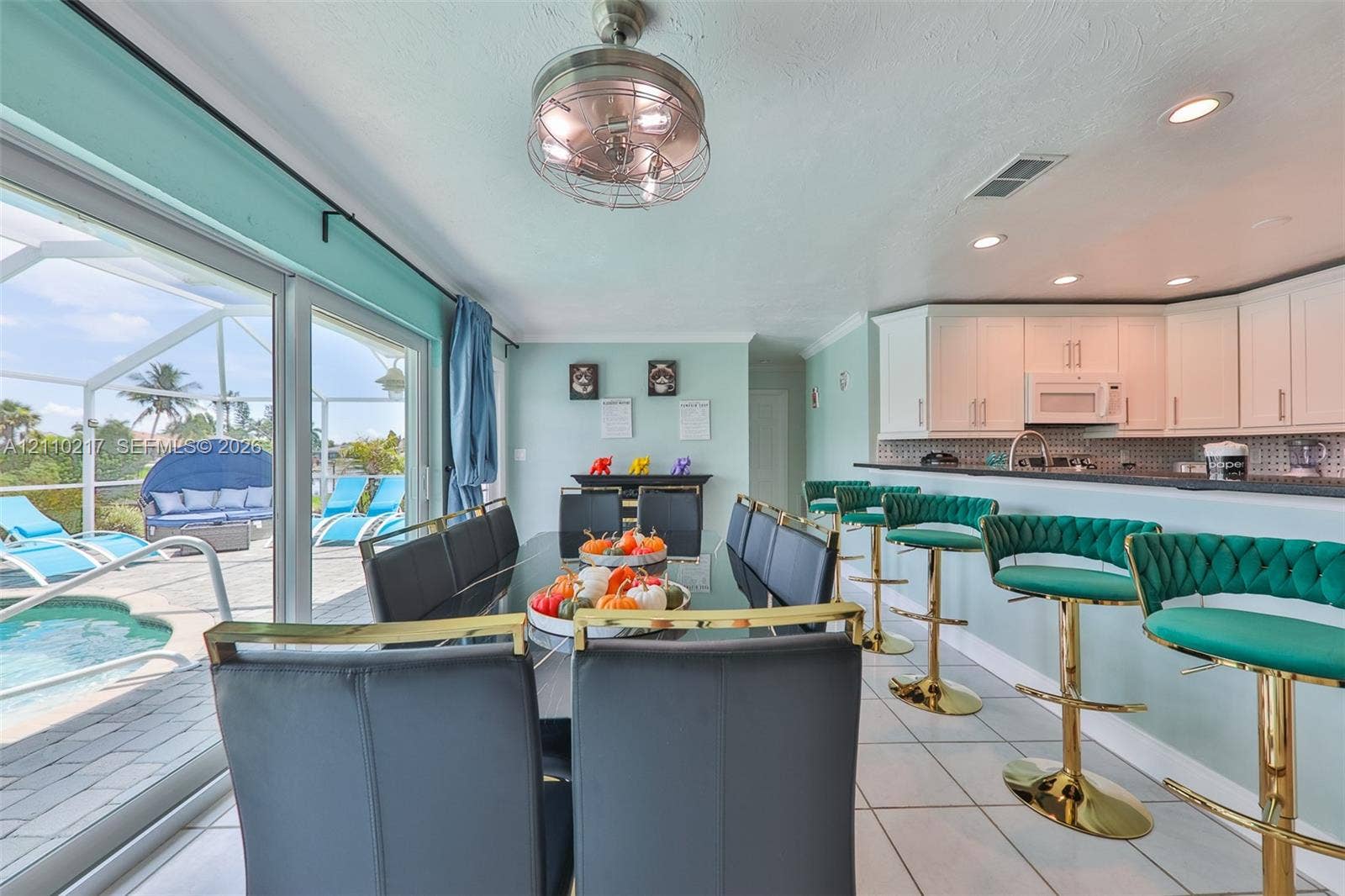 503 SW 17 Street, Cape Coral, FL 33990 Open-concept kitchen and dining area featuring white shaker-style cabinetry, dark stone countertops, recessed lighting, and expansive sliding glass doors leading to a screened lanai with a swimming pool