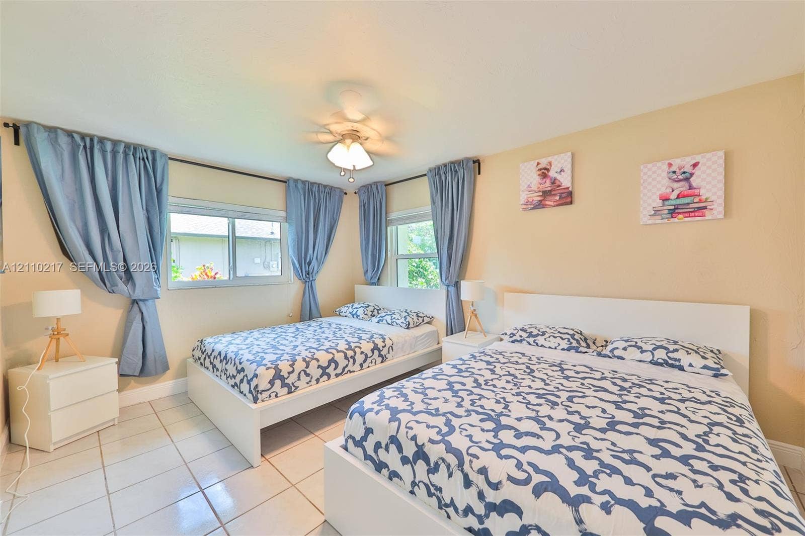 503 SW 17 Street, Cape Coral, FL 33990 Neutral interior space featuring white tiled flooring, two dual-pane windows with sliding glass panels, and a central ceiling fan with integrated lighting