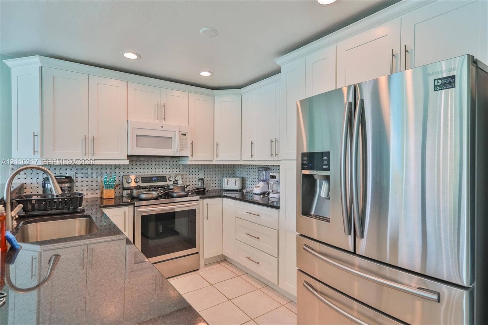 503 SW 17 Street, Cape Coral, FL 33990 Kitchen featuring white shaker-style cabinetry, dark stone countertops, stainless steel appliances, a mosaic-tiled backsplash, and recessed ceiling lighting