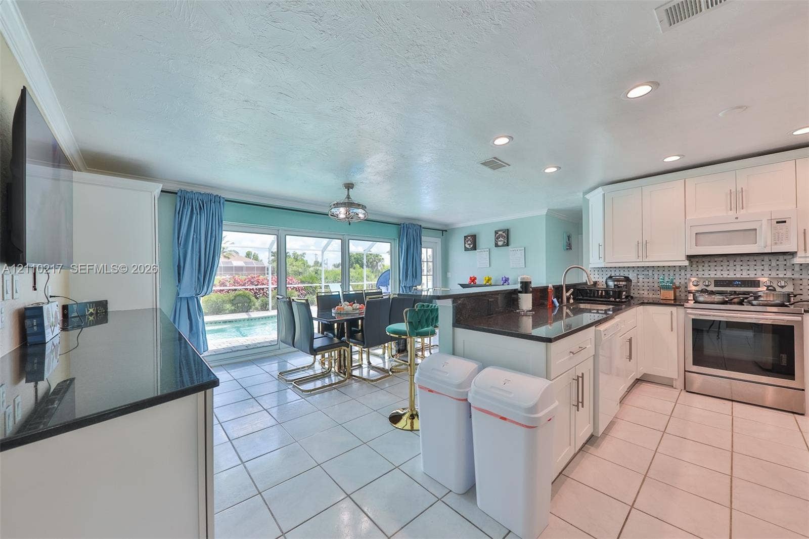 503 SW 17 Street, Cape Coral, FL 33990 Kitchen featuring white cabinetry, dark countertops, a stainless steel range, ceramic tile flooring, and large sliding glass doors
