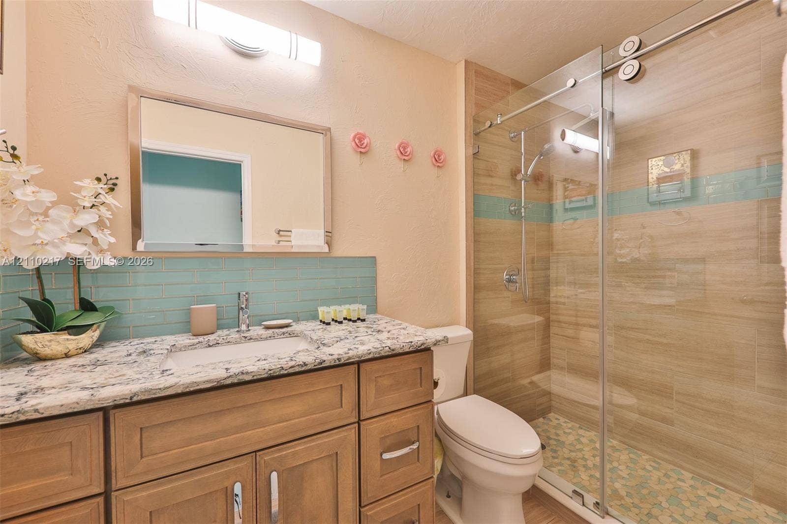 503 SW 17 Street, Cape Coral, FL 33990 Bathroom vanity featuring a stone-look countertop, undermount sink, blue subway tile backsplash, and wood-finish cabinetry