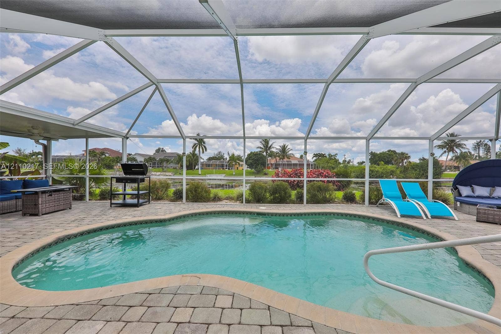 503 SW 17 Street, Cape Coral, FL 33990 Screen-enclosed patio featuring a curved swimming pool, paver hardscaping, and a white aluminum frame