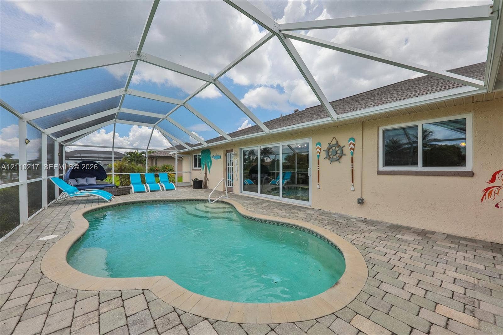 503 SW 17 Street, Cape Coral, FL 33990 Screened-in patio featuring a paver deck and an in-ground swimming pool with integrated steps